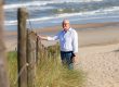 Stembevrijder Lambert staat bij een hek aan het strand