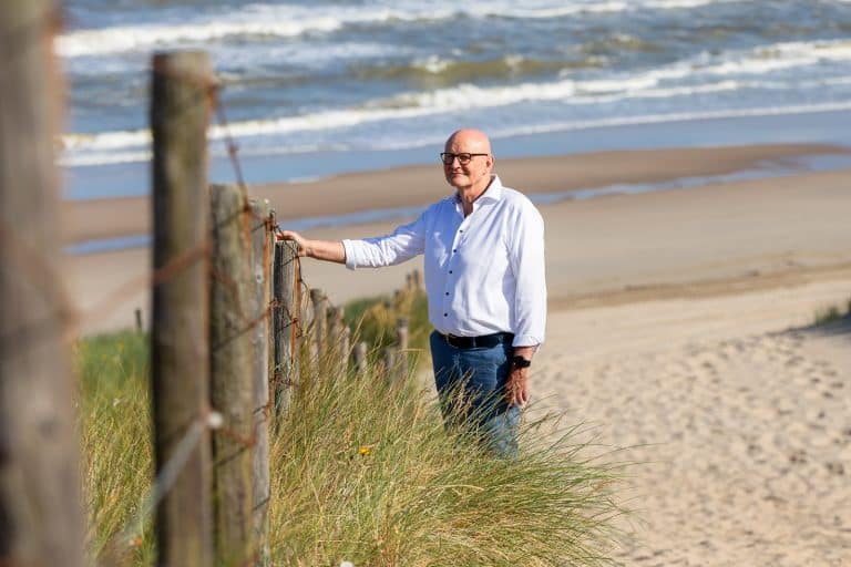 Stembevrijder Lambert staat bij een hek aan het strand