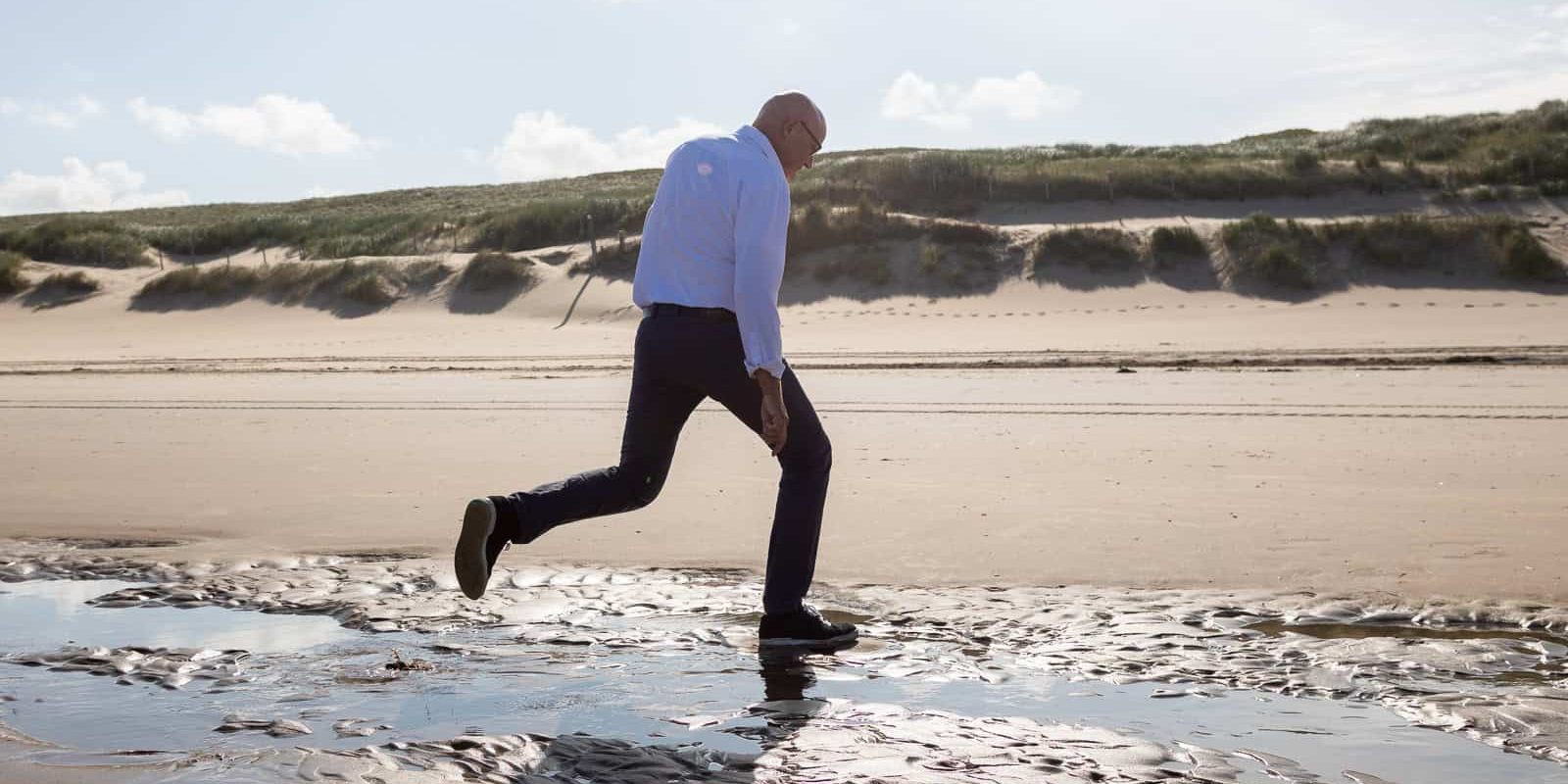 springen strand Stembevrijder Lambert springt over waterstroompje strand